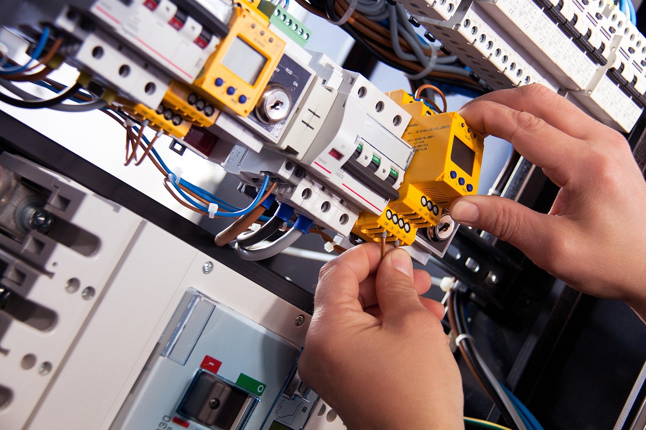 An electrician measuring electrical current at a wall thermostat box during a baseboard replacement project.