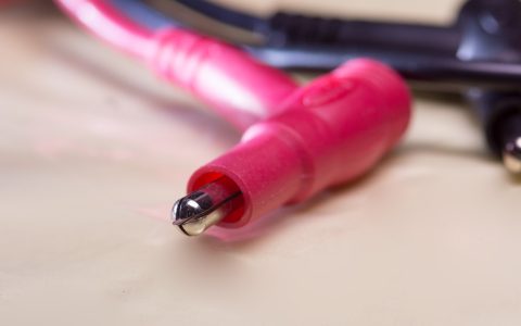 A technician using a digital multimeter to perform a continuity test on an unmounted electric oven bake element.