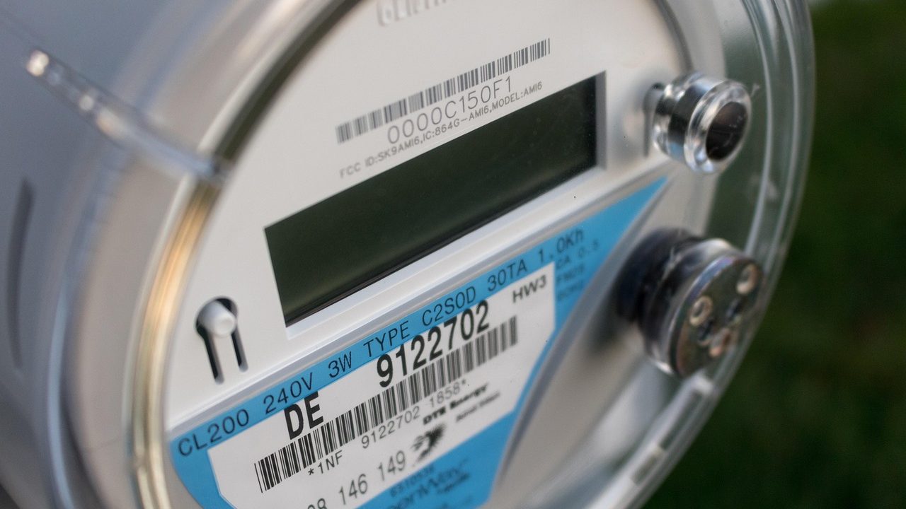 An electric utility meter and a monthly power bill laid out with a calculator and pen for a rate audit.
