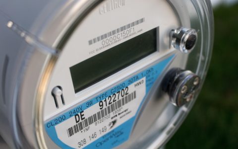 An electric utility meter and a monthly power bill laid out with a calculator and pen for a rate audit.