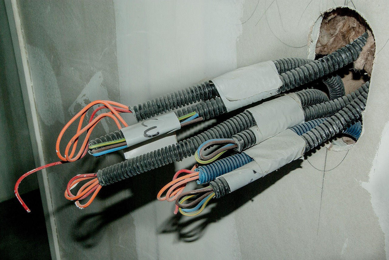 An electrician landing heavy feeder wires onto main breaker bus bars.