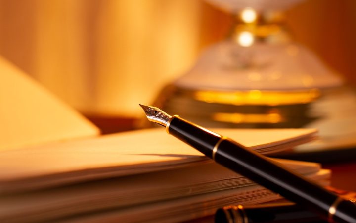 An employment agreement laying on a mahogany desk beside a fountain pen in a corporate office setting.