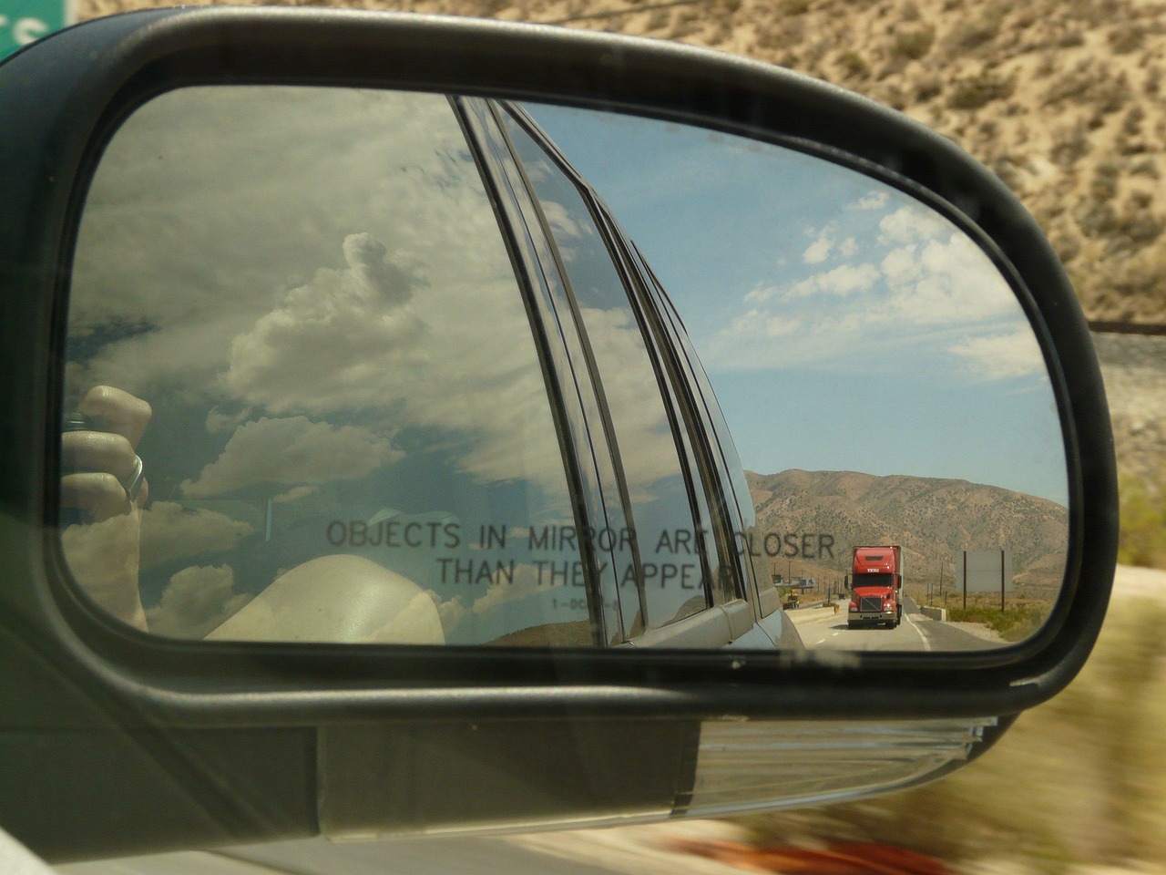 Electronic toll transponder mounted near a vehicle rearview mirror.