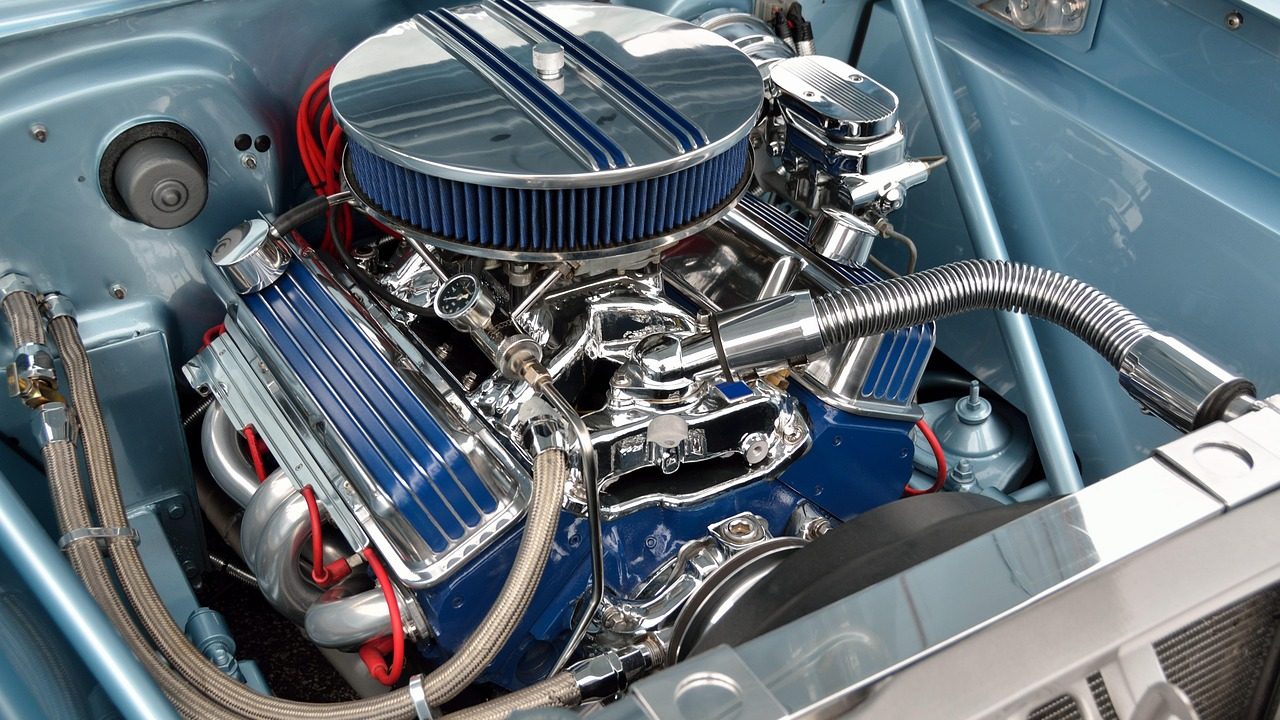A mechanic inspecting an engine under the hood of a modern car on a lift in a professional repair shop.