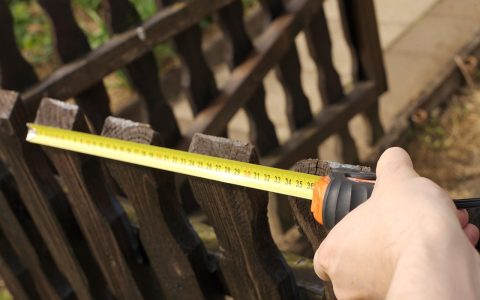 Contractor measuring a residential yard for a new fence installation