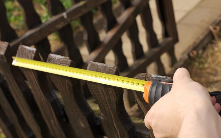 Contractor measuring a residential yard for a new fence installation
