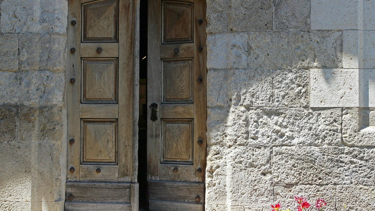 A carpenter installing a solid wood front door in a residential home.