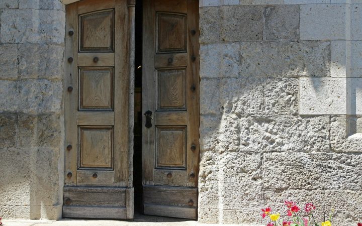A carpenter installing a solid wood front door in a residential home.