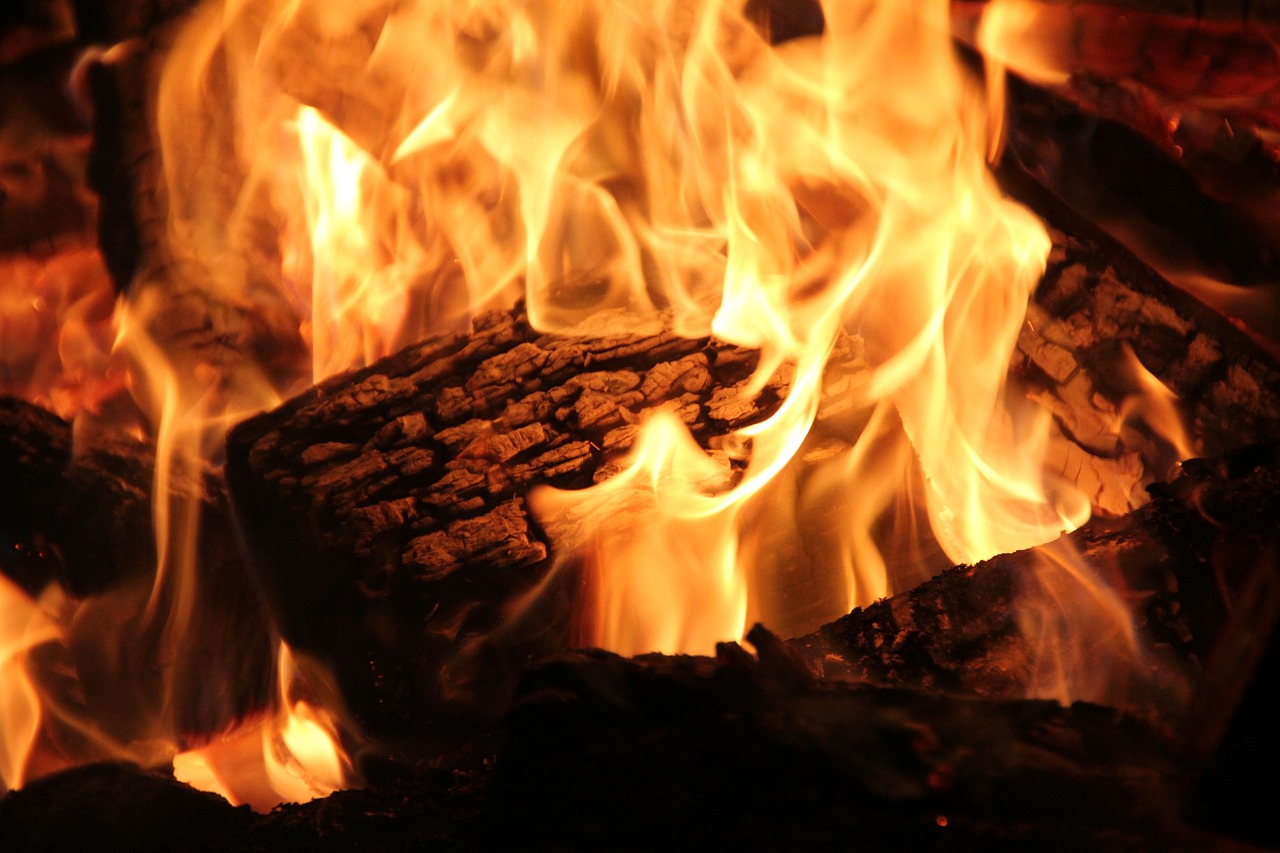 A chimney sweep inspecting the interior components of a wood-burning fireplace insert.