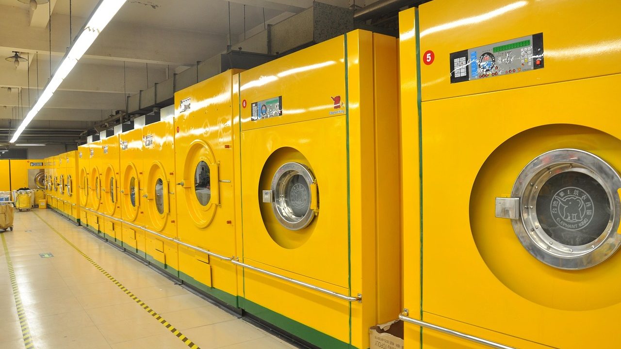 Side-by-side front load and top load washing machines in a well-lit modern American laundry room.
