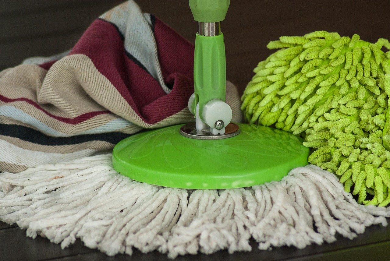 Cleaning supplies including bleach, hydrogen peroxide, microfiber cloths, and soft scrub brush arranged on a counter.