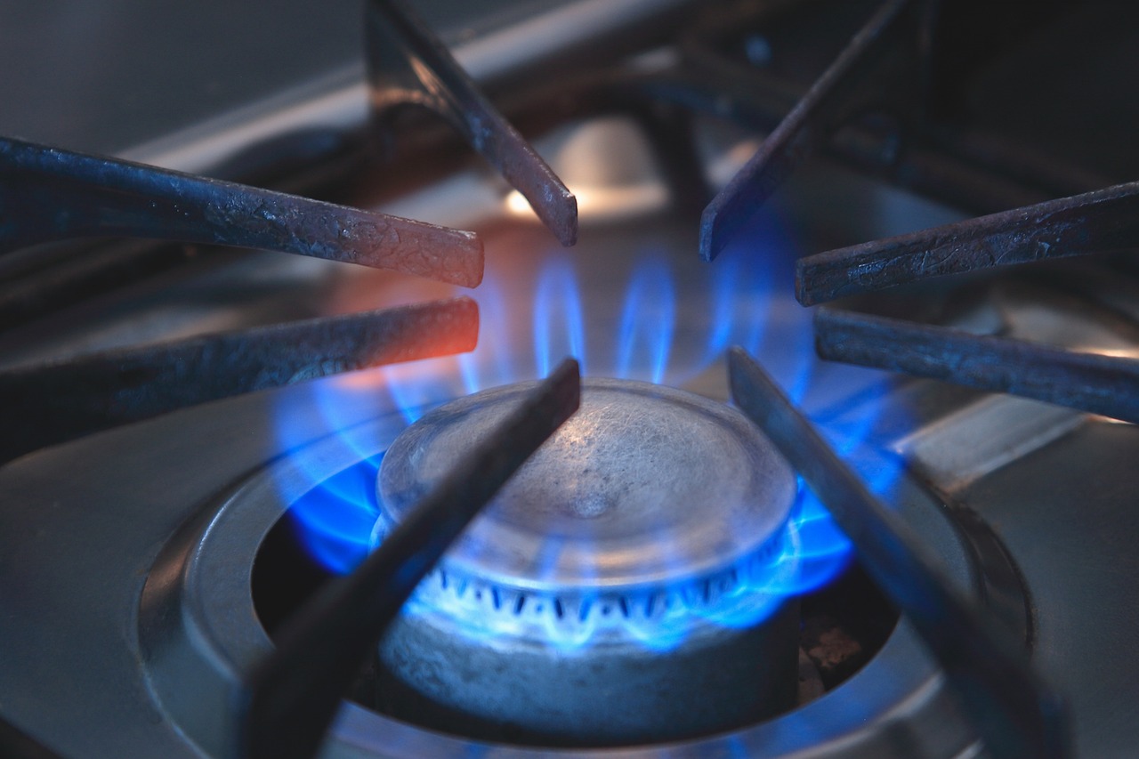 Hands of a technician checking components beneath a gas stove cooktop
