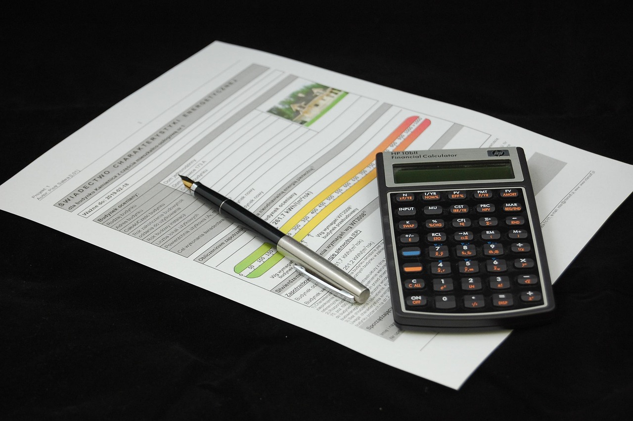 A calculator sitting beside loan payoff documents and a tablet displaying market valuation data.