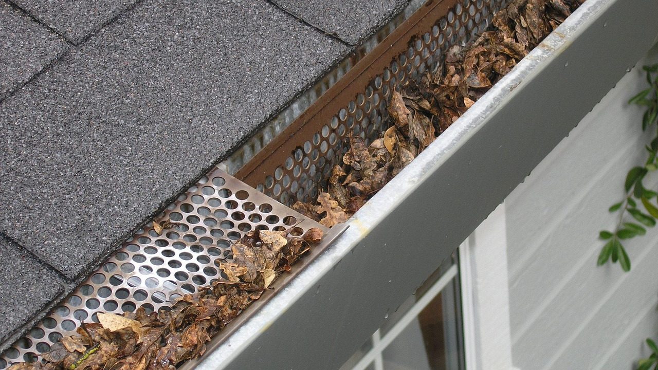 Contractor installing metal gutter protection on a residential roofline.
