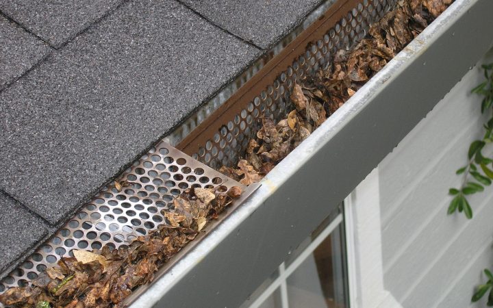 Contractor installing metal gutter protection on a residential roofline.