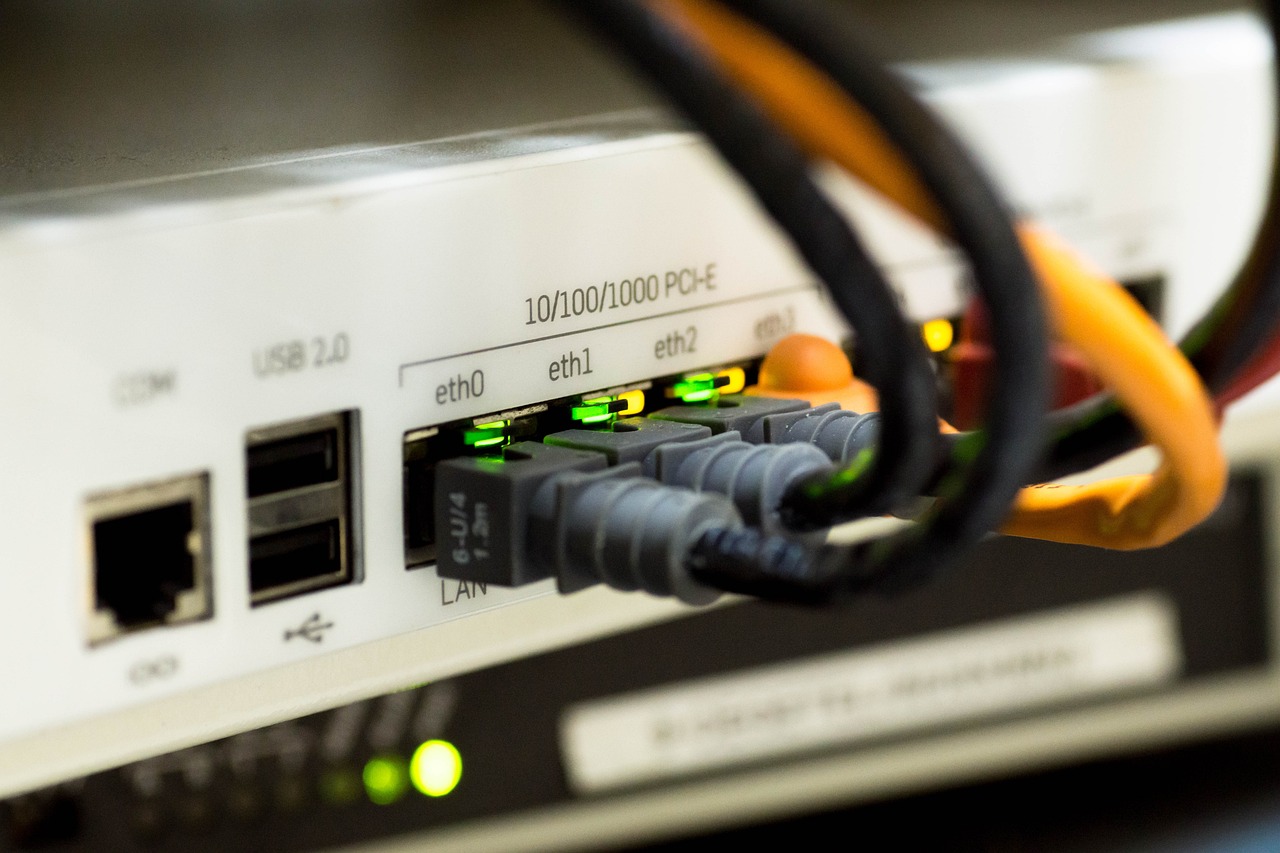 Close-up of an enterprise USB-C Ethernet adapter plugged into a laptop with a network cable inserted.