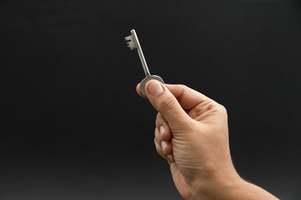 A hand activating a FIDO2 hardware security key touch sensor on a desktop keyboard at a shared office terminal.