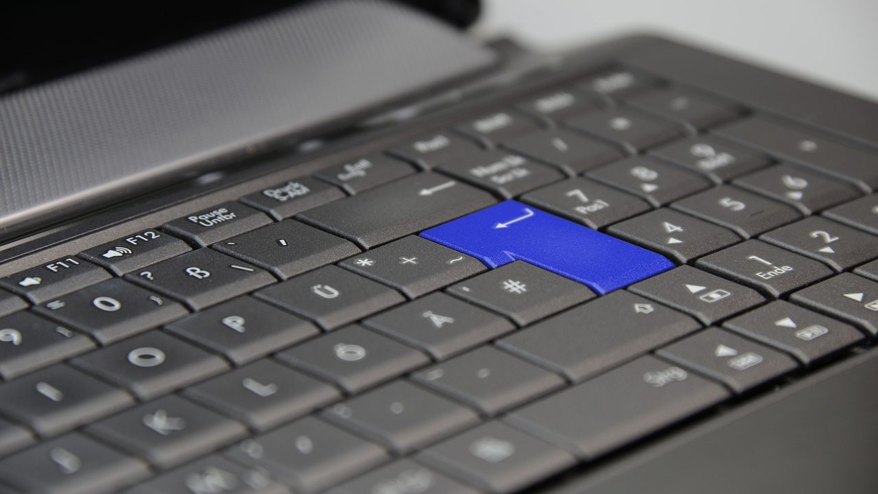 A hardware security key inserted into a USB-C port on a developer laptop in a remote workspace.