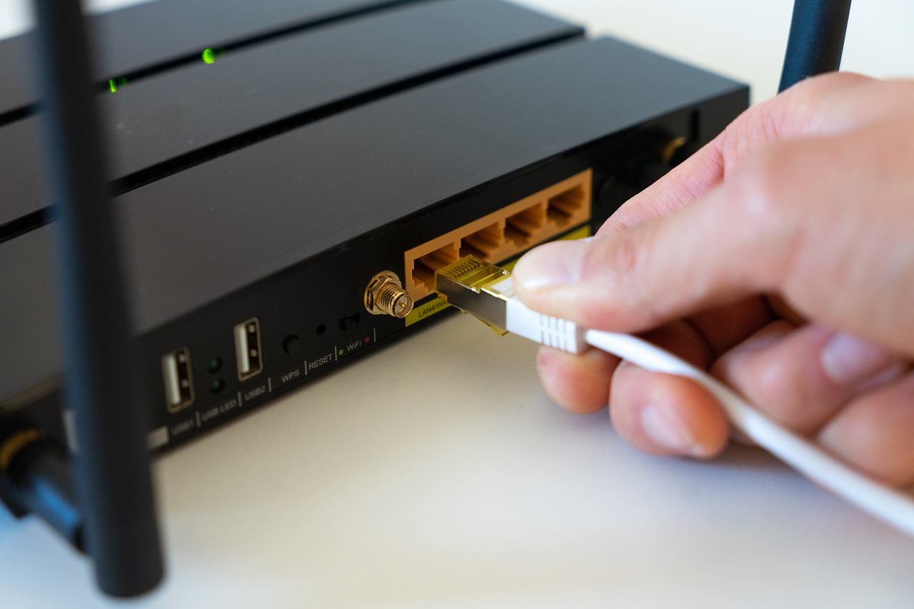 Close-up of hands plugging an ethernet cable into a portable travel router