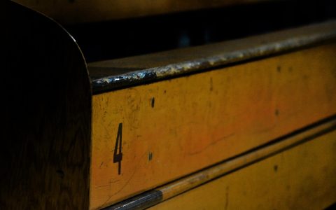 A high school athlete sitting thoughtfully on a gymnasium bench after tryouts.