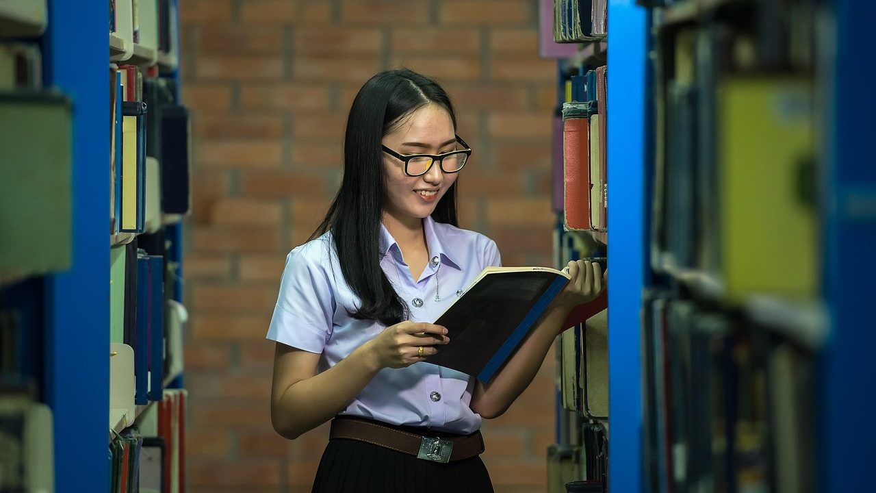 A high school student and parent reviewing college course enrollment and textbook documentation with a school guidance counselor.