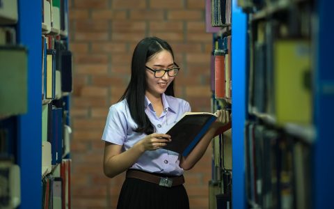 A high school student and parent reviewing college course enrollment and textbook documentation with a school guidance counselor.