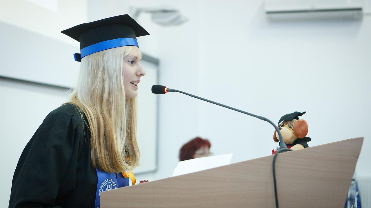 A graduating senior standing at a podium giving a speech during a commencement ceremony.