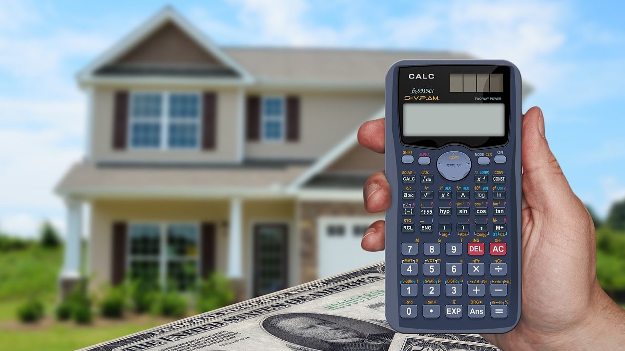 Real estate closing documents, calculator, and house keys on a wooden desk.