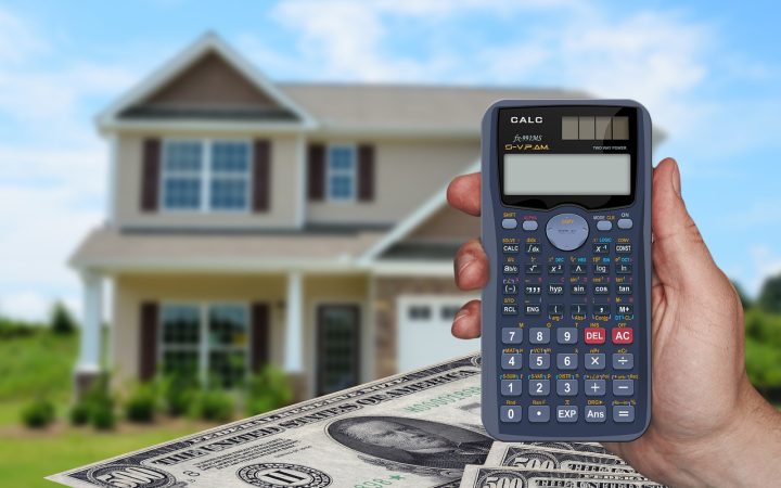 Real estate closing documents, calculator, and house keys on a wooden desk.