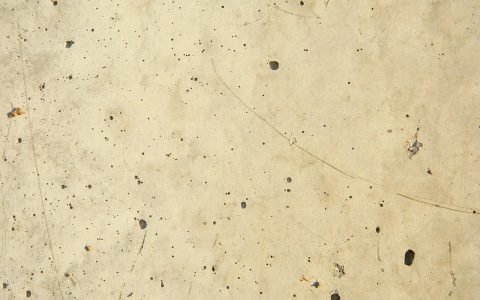 A homeowner using a pressure washer to clean a concrete patio surface outdoors.