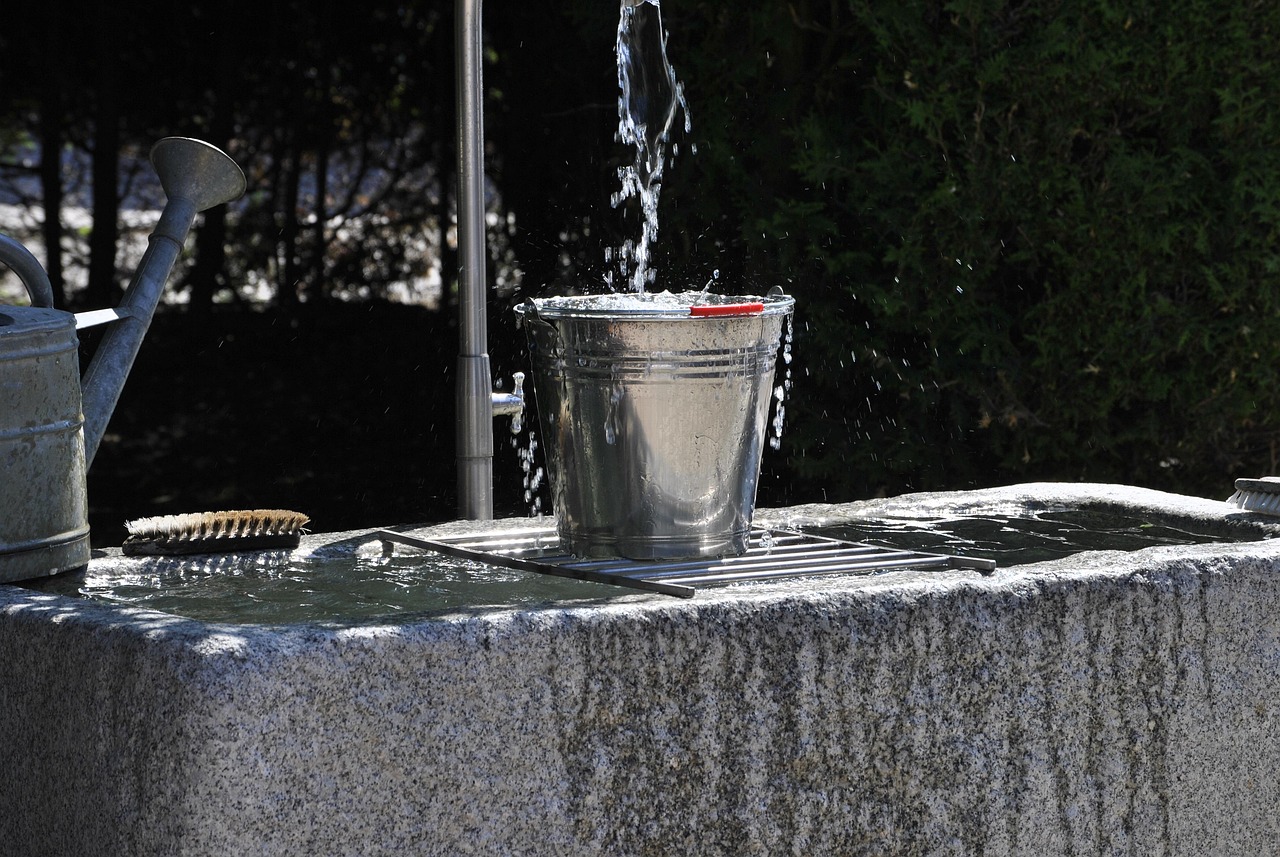 Bucket of soapy cleaning solution with sponge for exterior home maintenance
