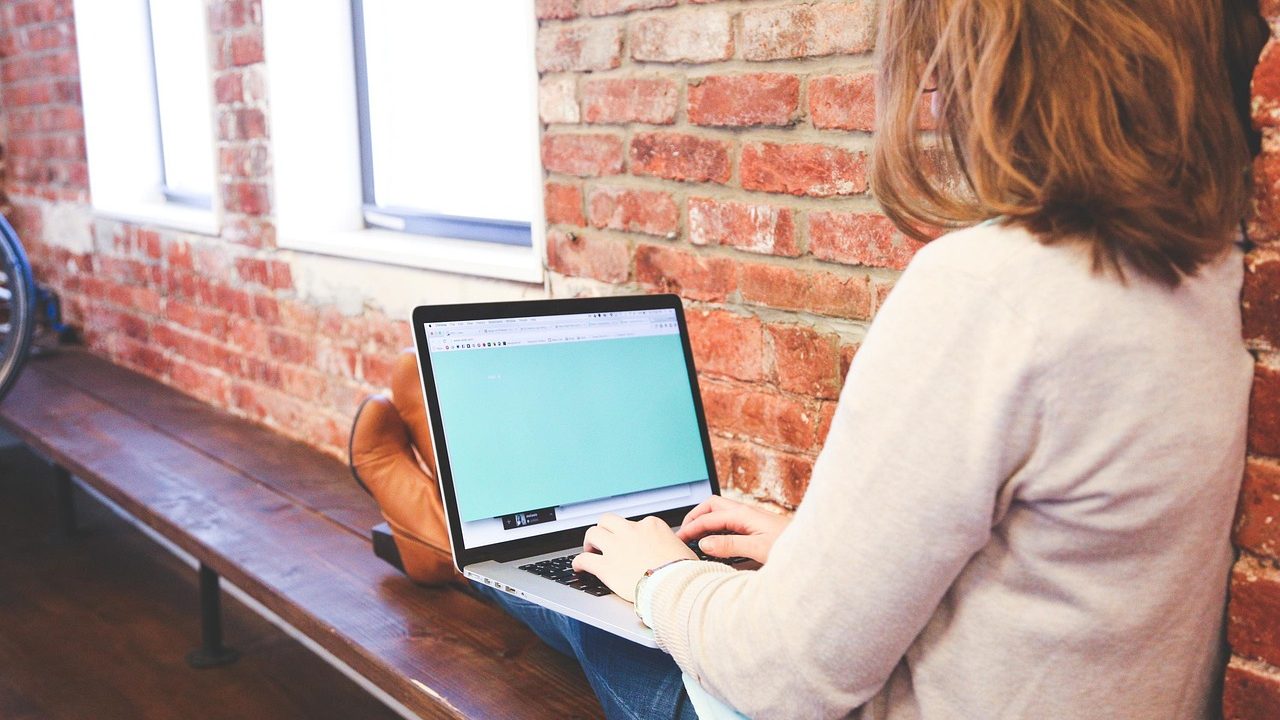 A focused professional calmly reviewing notes and working on a laptop in a modern corporate office.