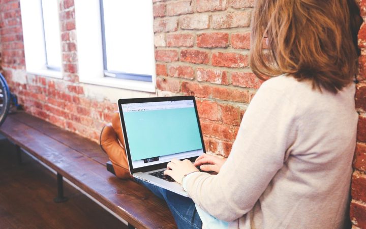 A focused professional calmly reviewing notes and working on a laptop in a modern corporate office.