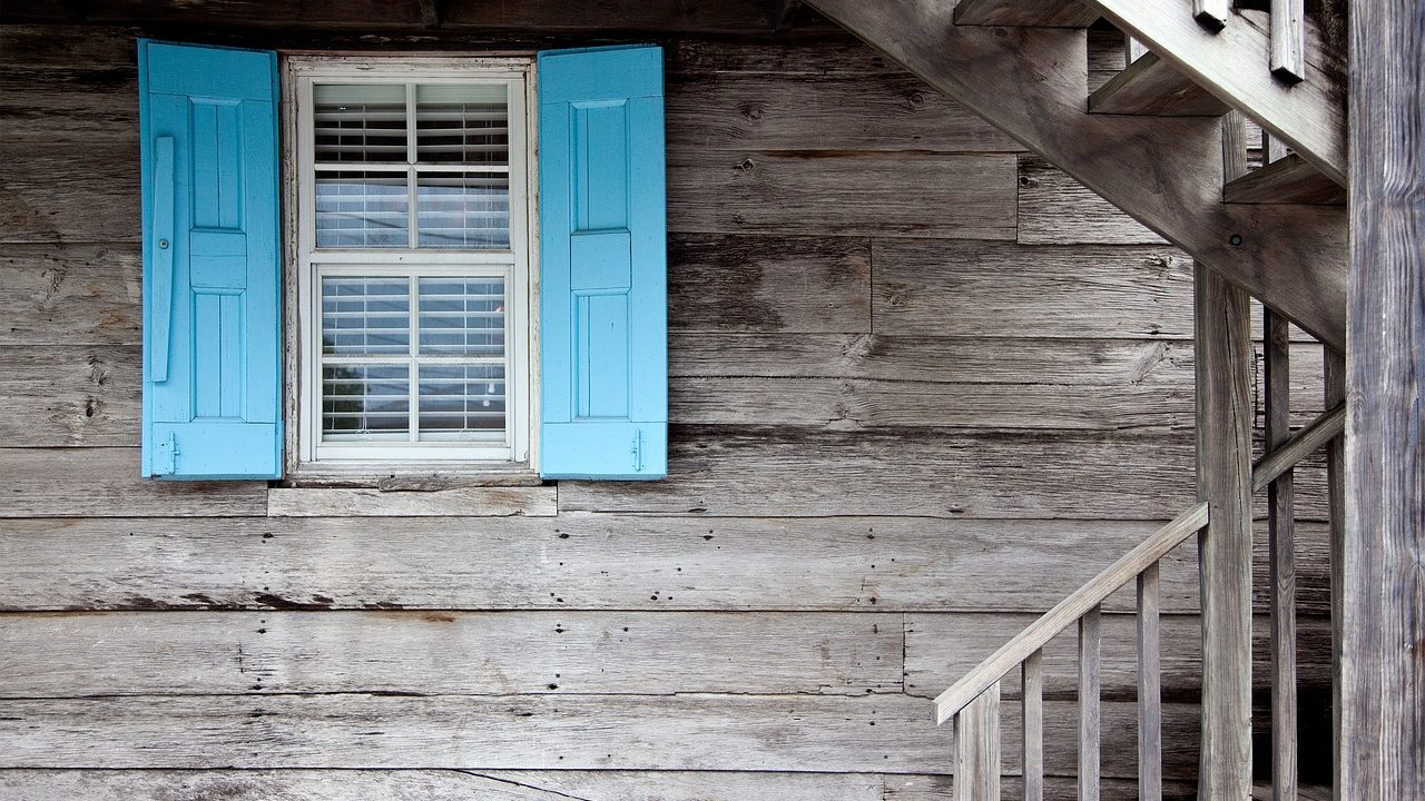 Close-up of a carpenter using a hand plane on a wooden window sash.