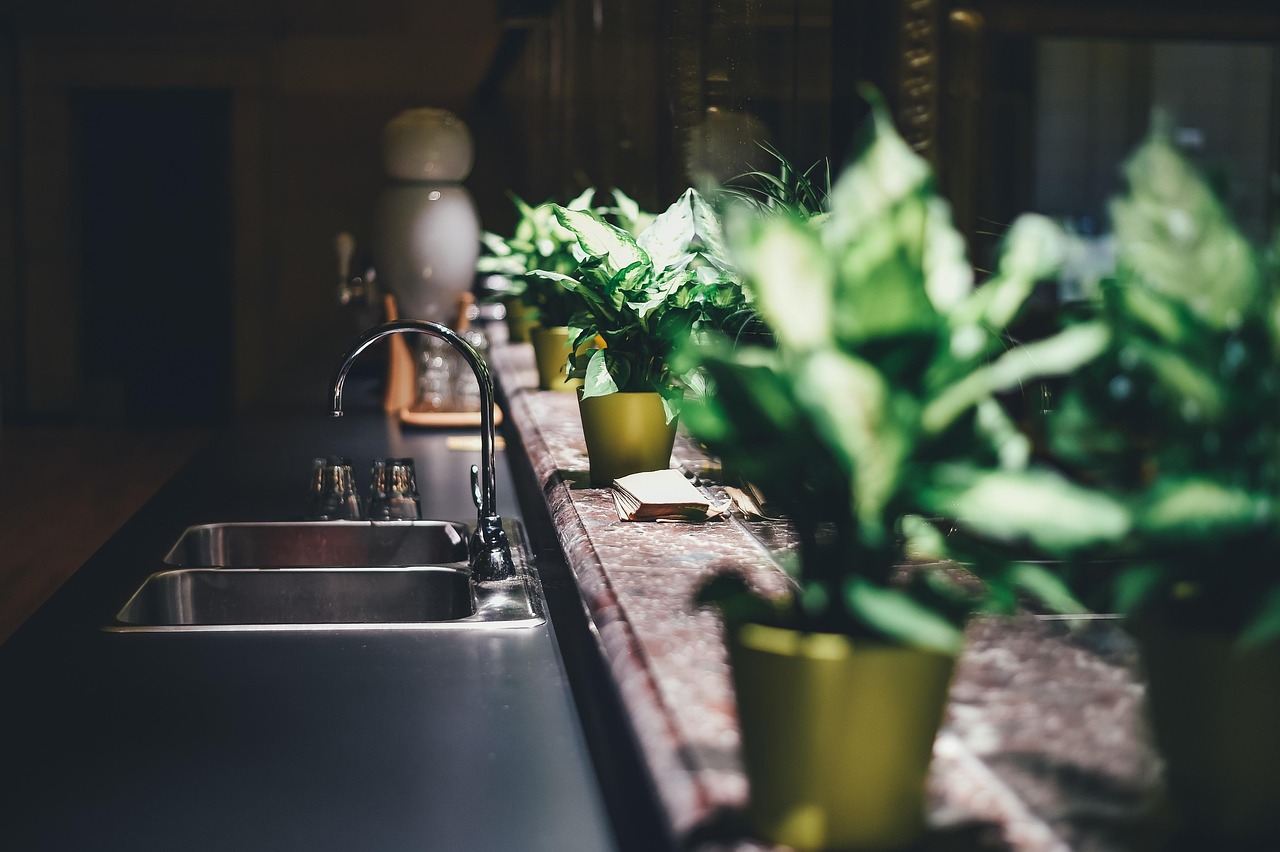 Flashlight illuminating the inside of a kitchen sink drain while pliers extract a blockage from the disposal plate.