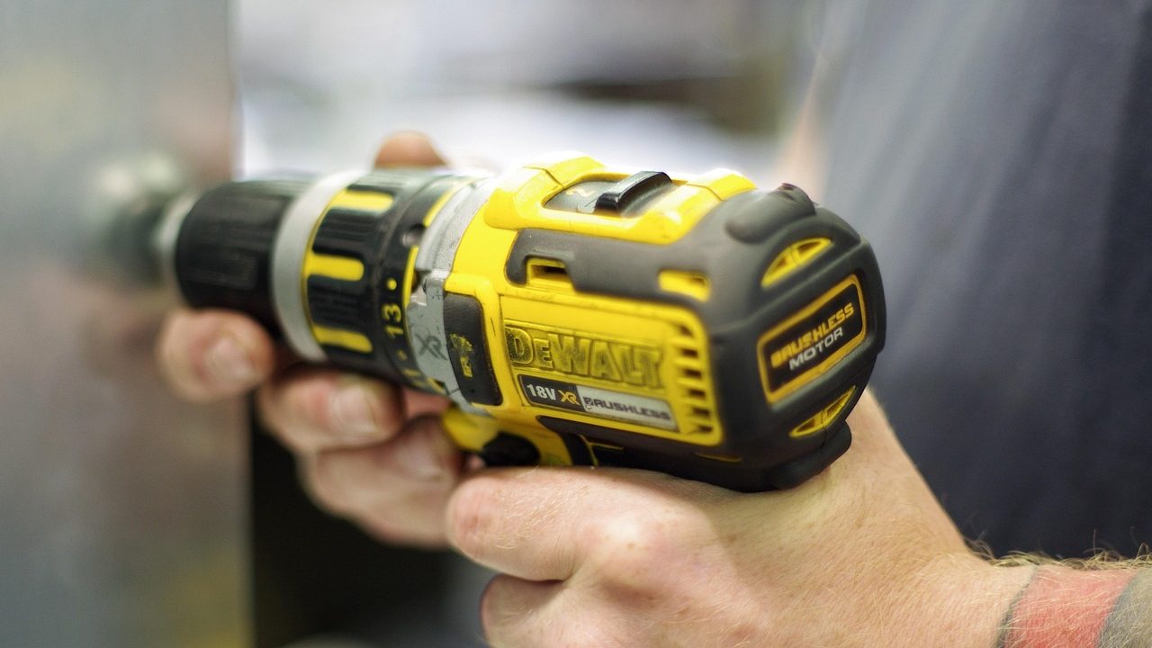 Driving a score-line fastener into an oak hardwood floor with a cordless drill alignment tool.