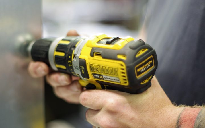 Driving a score-line fastener into an oak hardwood floor with a cordless drill alignment tool.