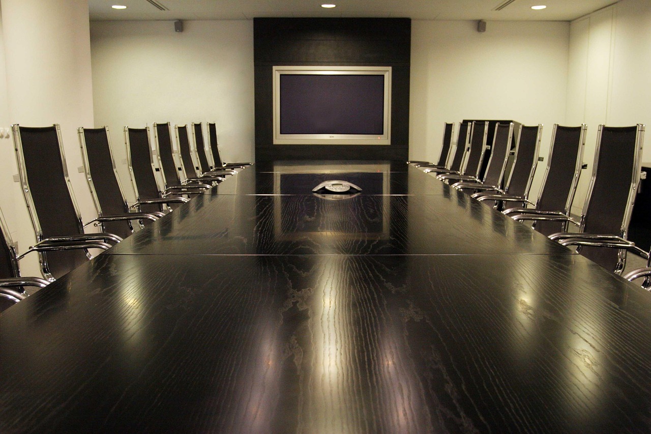 Two corporate professionals in a private glass meeting room discussing official performance documents.