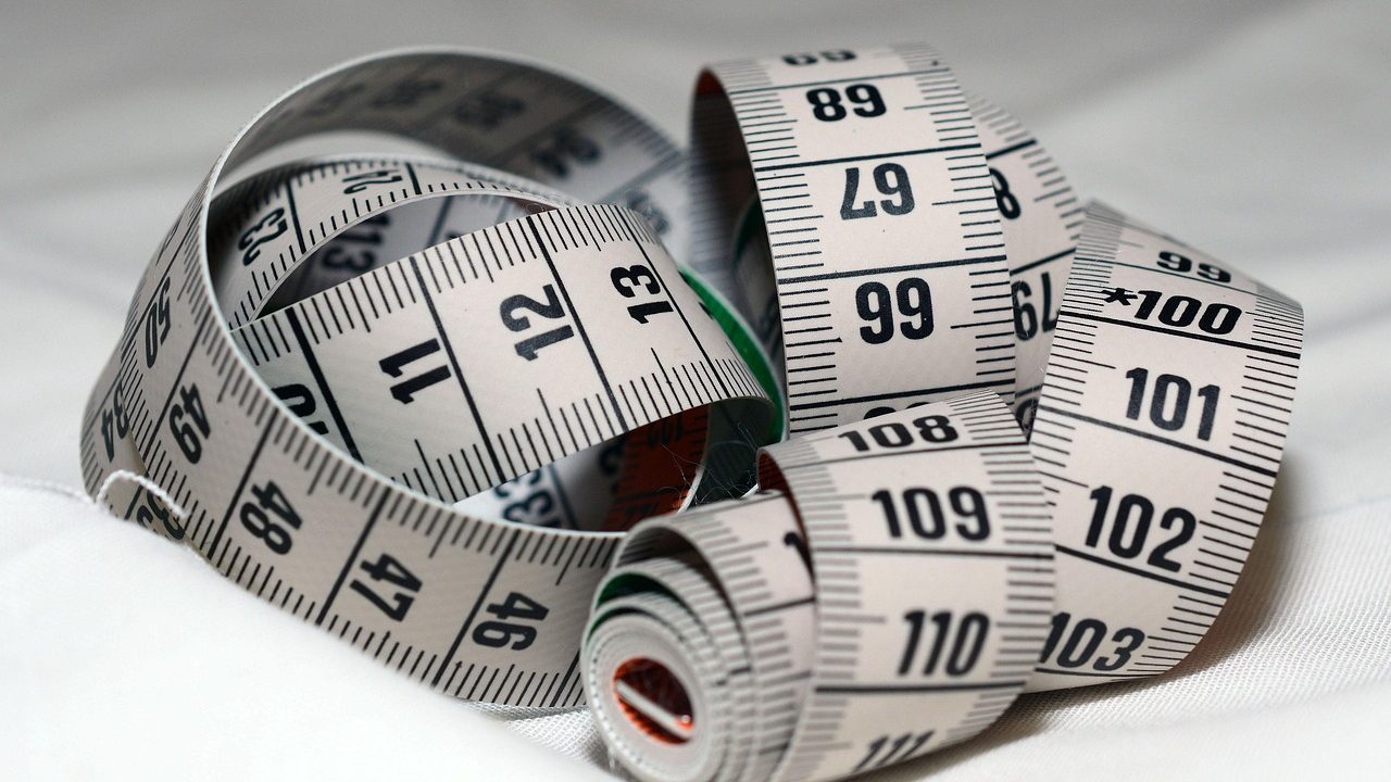 Architectural blueprints, a tape measure, and material samples arranged on a kitchen counter during a home remodeling project.