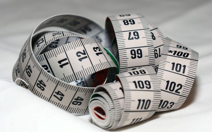 Architectural blueprints, a tape measure, and material samples arranged on a kitchen counter during a home remodeling project.