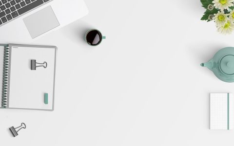A clean, organized desk workspace with a laptop and notebook representing digital order.
