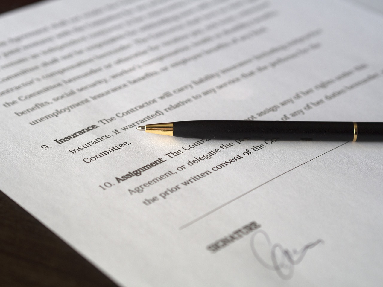 Close-up of a contract and legal paperwork on a wooden desk.