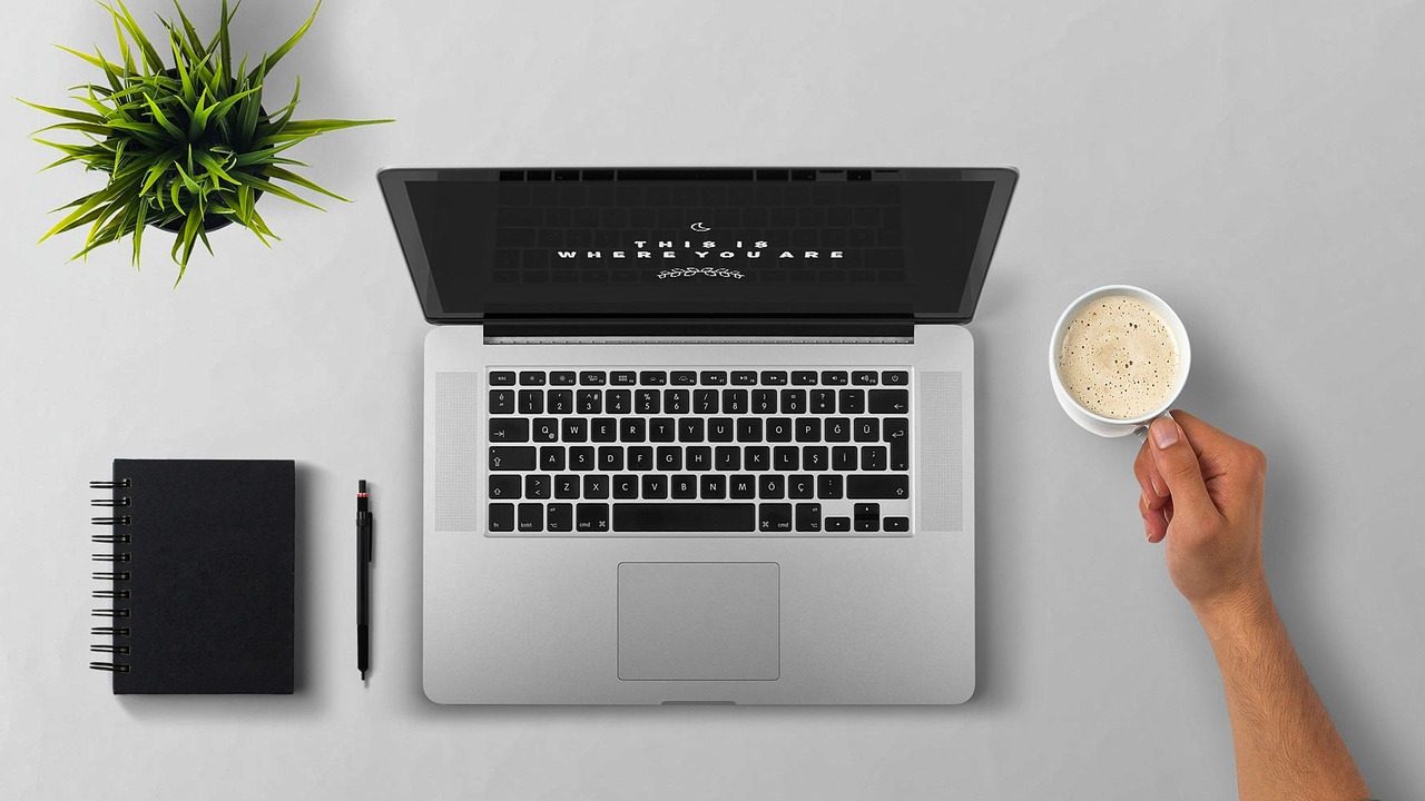 Corporate professional reviewing a document on a laptop at a clean desk.