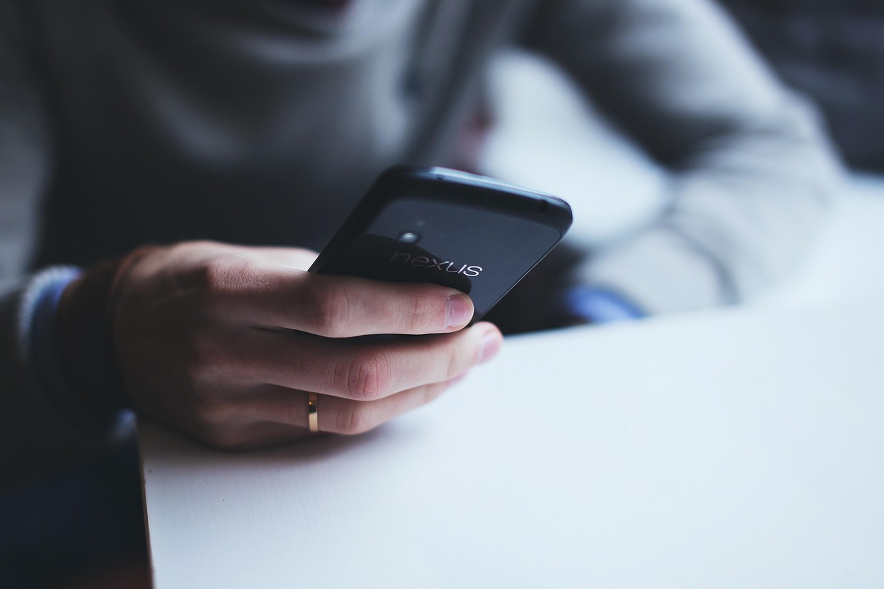 Hands holding a smartphone setting up automated sub-account bank transfers for savings goals.