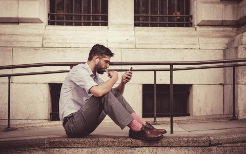 A person looking closely at a smartphone screen while sitting at a desk.