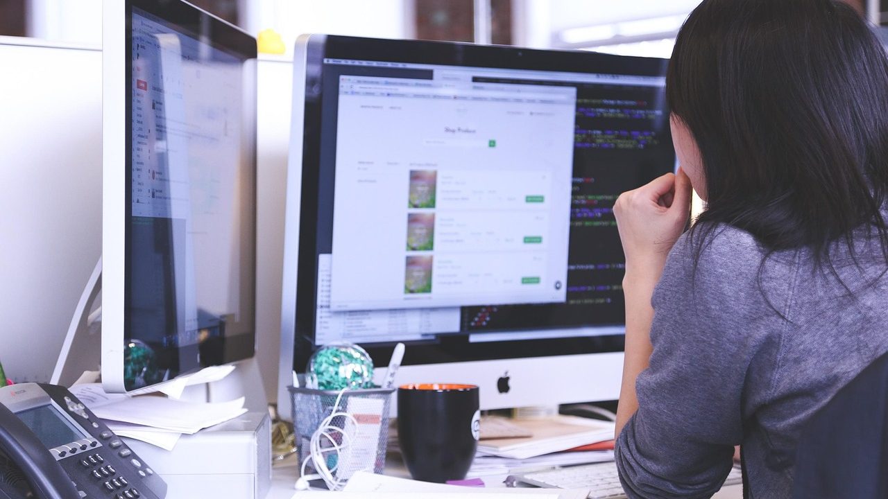 A corporate professional reviewing business documents and a laptop in a bright modern office conference room.