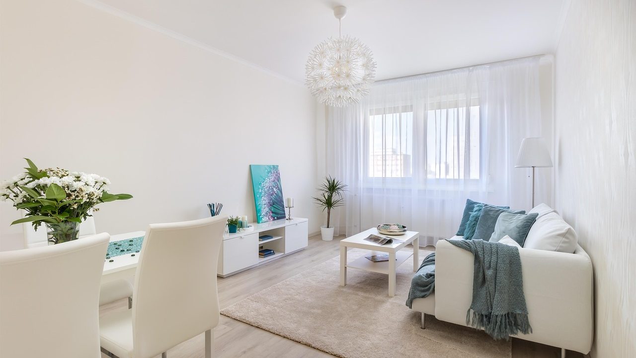 A modern, clean apartment living room featuring an automatic litter box and a sleek HEPA air purifier seamlessly integrated into the home decor.