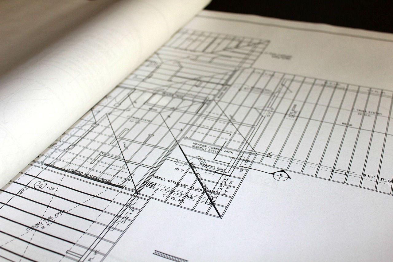 A contractor and a homeowner reviewing blueprints and structural framing estimates at a kitchen table.