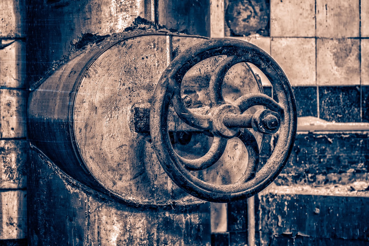 An old corroded multi-turn brass gate valve showing corrosion and leaks near the packing nut