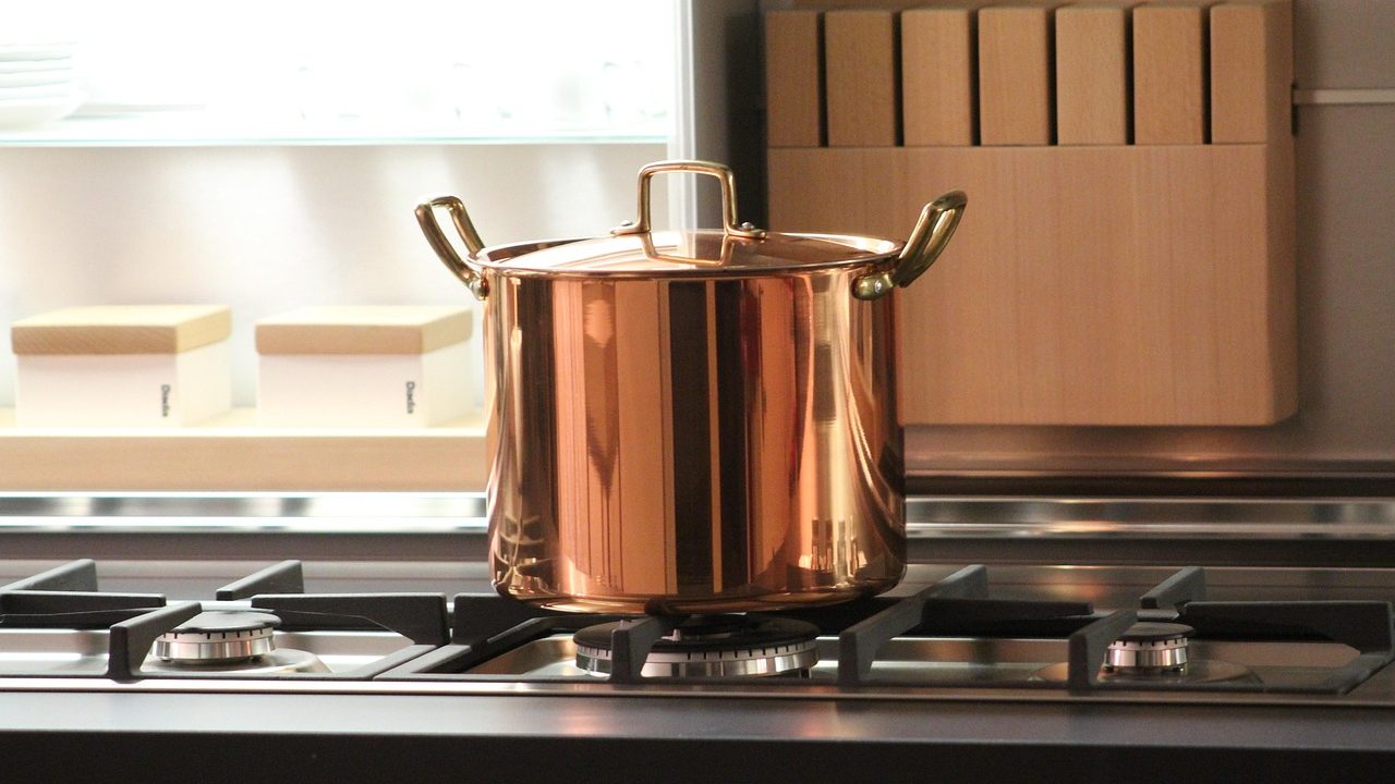 A modern quarter-turn brass ball valve installed on a residential main copper water line